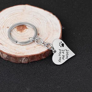 Macro view of heart-shaped keychain with You Had me At Woof text and paw print engraving