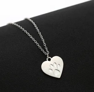 Dettaglio ravvicinato di una collana con ciondolo a cuore argento e zampa di cane