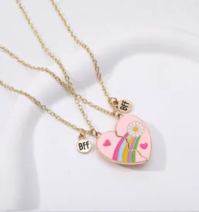 Detail of gold BFF heart necklaces with pink enamel daisy and rainbow patterns