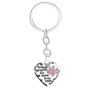 Macro detail of silver heart pendant featuring pink rhinestone paw print and engraved quote
