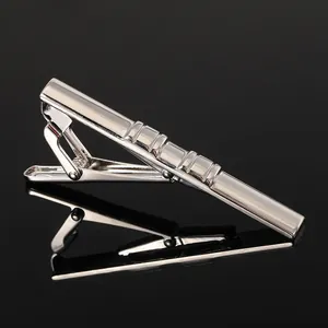 Close-up of polished silver tie clip with horizontal groove pattern and spring alligator clip