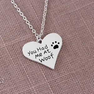 Dettaglio della collana con ciondolo a cuore e incisione You Had Me At Woof e zampa