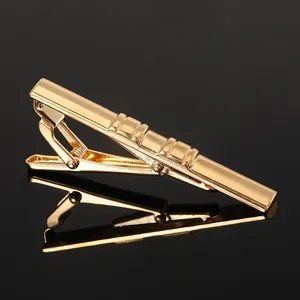 Detailed macro view of the gold-plated metal tie clip with four horizontal decorative grooves
