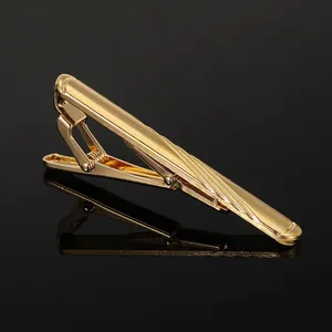 Macro detail of golden metal tie clip with diagonal textured stripes on black reflection