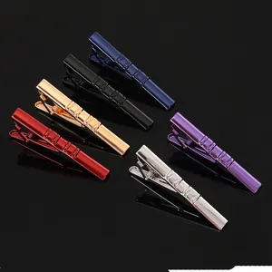 Detail of six colored metal tie clips with textured diagonal stripes on black surface