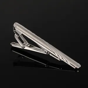 Close-up of polished silver tie clip with streamlined diagonal stripes on black background