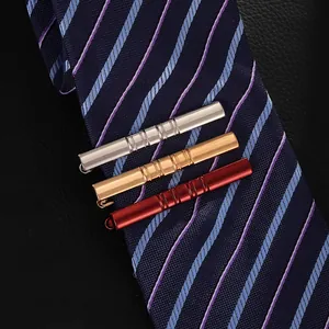 Detailed close-up of three metal tie clips in gold, silver, and red on blue silk tie