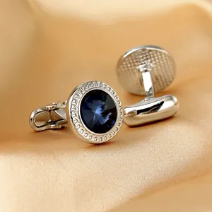 Details von silbernen Manschettenknöpfen mit blauem Kristall auf goldener Seide