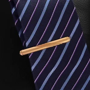 Detailed macro view of a gold metallic tie clip with diagonal grooves on a navy striped tie