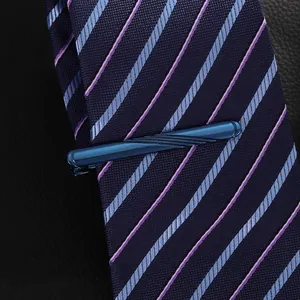 Detailed close-up of dark blue metallic tie clip with slanted brushed texture on striped tie