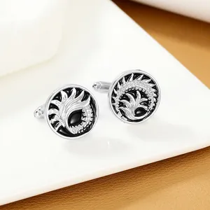 Macro shot of silver cufflinks with black enamel and embossed silver feather patterns