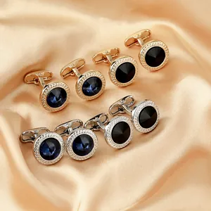Detail von runden Gold- und Silbermanschettenknöpfen mit blauen Kristallen auf Seide