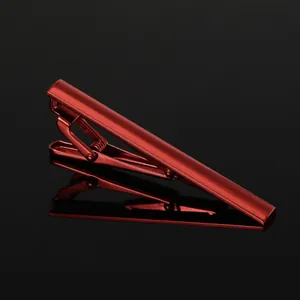 Detailed macro view of the polished metallic red tie clip with spring clamp on black glass