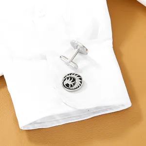 Detail of silver totem cufflinks on a white shirt sleeve against brown leather background