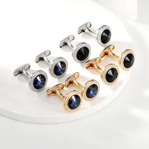 Detailansicht runder Manschettenknöpfe in Gold und Silber mit blauen Kristallen