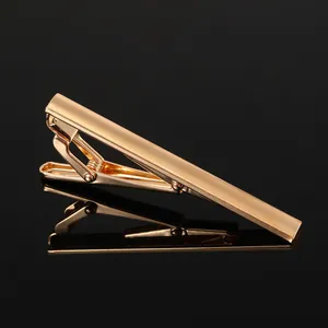 Detailed macro view of the polished gold tie clip with smooth metallic finish on black background
