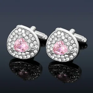 Dettaglio macro di gemelli da uomo in argento con zircone rosa e pavé di cristalli