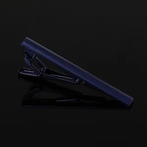 Macro shot of minimalist black matte tie clip with spring mechanism on mirror surface