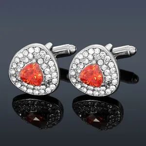 Dettaglio di gemelli triangolari in argento con pietre arancioni e strass scintillanti