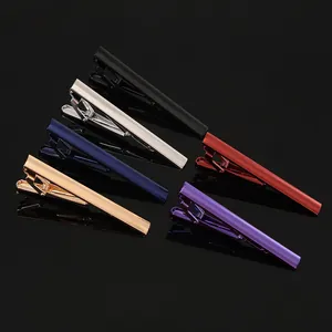 Close-up of six multicolor striped tie clips in polished brass on a black background