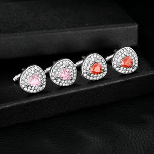 Dettaglio di gemelli argentati con cuore rosa e pietre rosse con accenti di diamanti brillanti