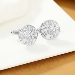 Detail of silver musical note cufflinks showing embossed treble clef on polished round surface
