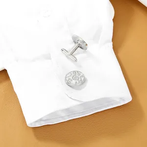 Detailed close-up of musical note cufflinks on white shirt cuff with leather background