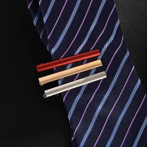 Three-piece metal tie clip set in burgundy, gold, and silver on navy textured tie