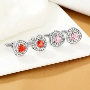 Dettaglio di gemelli da polso argentati con pietre rosse e rosa e intarsi in zirconi
