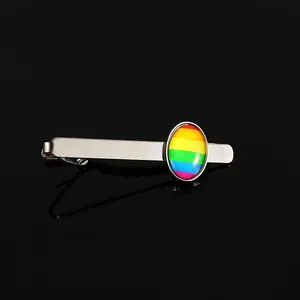 Détail d'un pince à cravate argenté avec incrustation arc-en-ciel sur fond noir