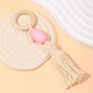 Detalle del anillo de dentición de madera con cuenta rosa y borla de algodón beige artesanal