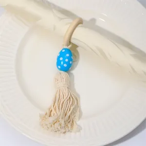 Detalle de un servilletero de madera natural con huevo azul de lunares y borla de algodón