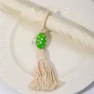 Detalle del servilletero de madera con cuenta de huevo de lunares verdes y borla crema