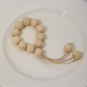 Servilletero artesanal de cuentas de madera con borlas de yute en plato blanco