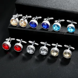 Macro view of round faceted crystal cufflinks in blue, red and champagne on black leather