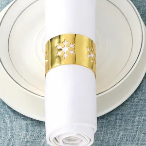 Detalle de servilletero dorado calado con diseño de copo de nieve en tela blanca