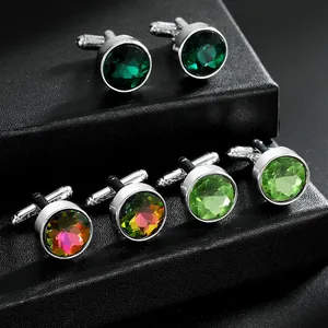 Three pairs of round colorful crystal cufflinks for men on a black textured background