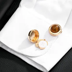 Macro shot of gold cufflink covers with brown tiger eye stone on a white shirt sleeve