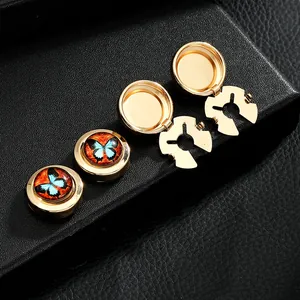 Macro shot of gold butterfly cufflinks with blue and orange enamel on black leather