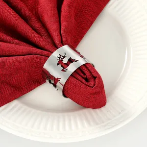 Detalle de servilletero metálico con reno plateado sobre servilleta roja y plato