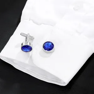 Polished silver cufflinks with round blue crystals on white shirt sleeve cuff