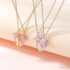Detail of gold and silver heart pendants with pink footprints on delicate cross chains
