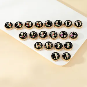 Detailed close-up of round alphabet cufflinks with floral patterns from A to J