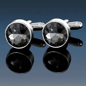 Close-up of polished silver cufflinks with faceted grey stones on a reflective surface