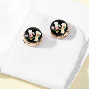 Detail of rose gold cufflinks with letter M and floral design on white shirt cuff