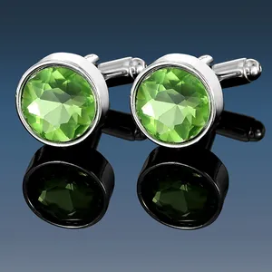 Macro shot of silver cufflinks featuring round faceted green crystals on reflective surface