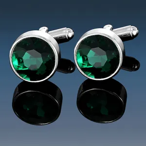 Macro view of silver-tone cufflinks featuring faceted emerald green round crystals
