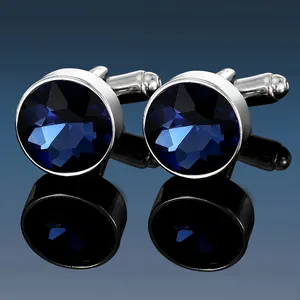 Macro shot of silver metal cufflinks featuring faceted navy blue crystal inlays and reflections