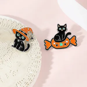Close-up of Halloween enamel pins featuring black cats with witch hats and candy designs
