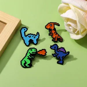Macro shot of four pixel art dinosaur enamel pins in vibrant colors on a green background
